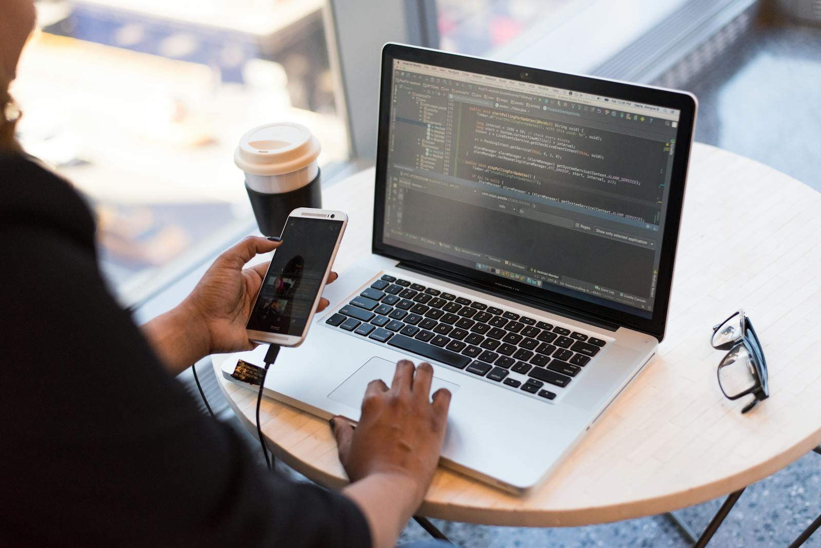 Developer using a laptop and smartphone during web and mobile application work